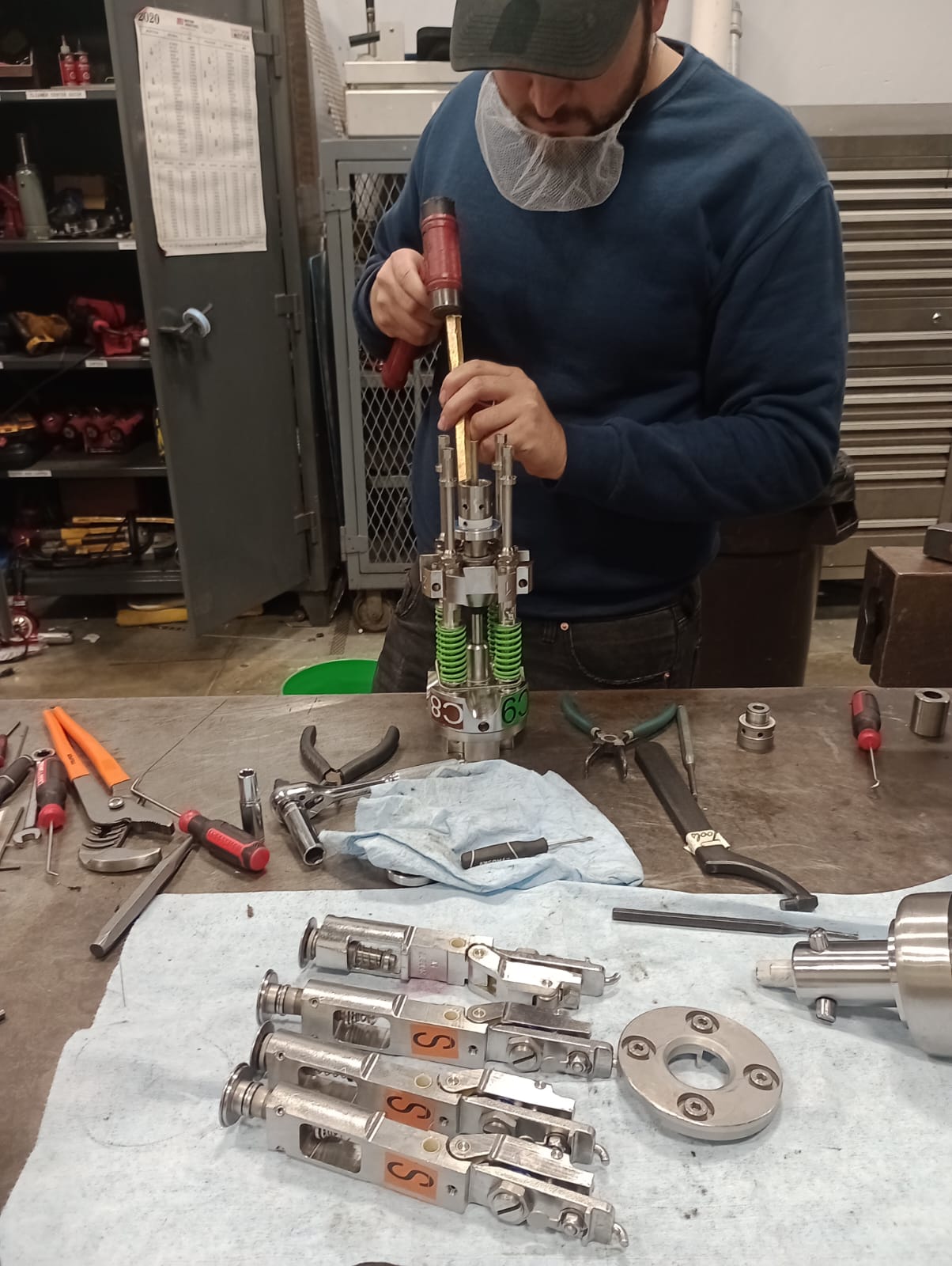 bXperts technician wearing an orange vest with bXperts branding, working on industrial machinery components during a retrofit or overhaul service